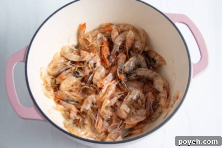 Savory Shrimp Stock from Scratch 6 Overhead view of shrimp shells and avocado oil in a large dutch oven on a neutral background.