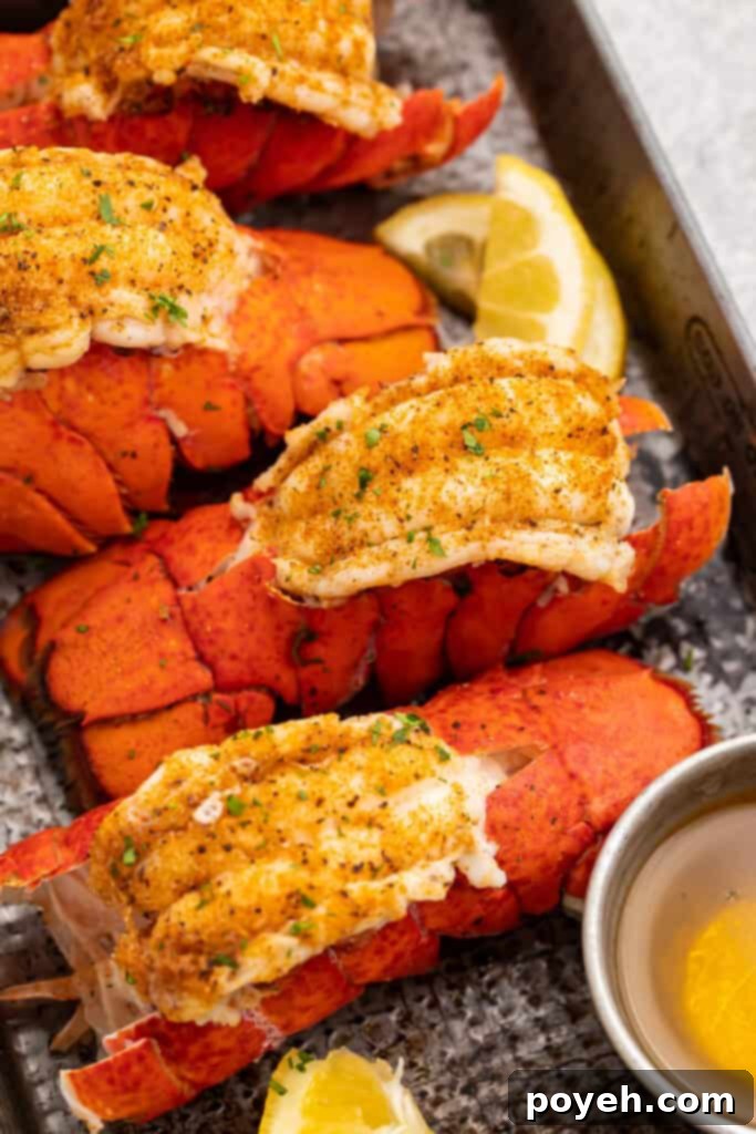Four bright red lobster tails cooked in an Instant Pot then butterflied and set on a baking sheet.