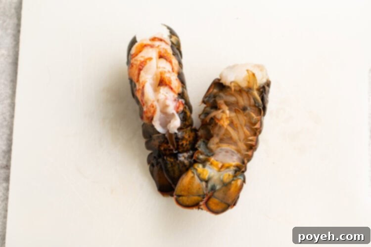 Overhead view of two lobster tails on a cutting board, with one flipped over to show ribs underneath tail.