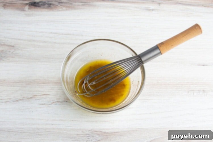 Overhead view of olive oil marinade for grilled broccolini in a glass mixing bowl.