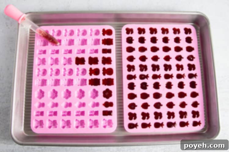 Sour Cherry Chews 9 Overhead view of two gummy molds partially filled with tart cherry gummy liquid, with a dropper of liquid on one mold.