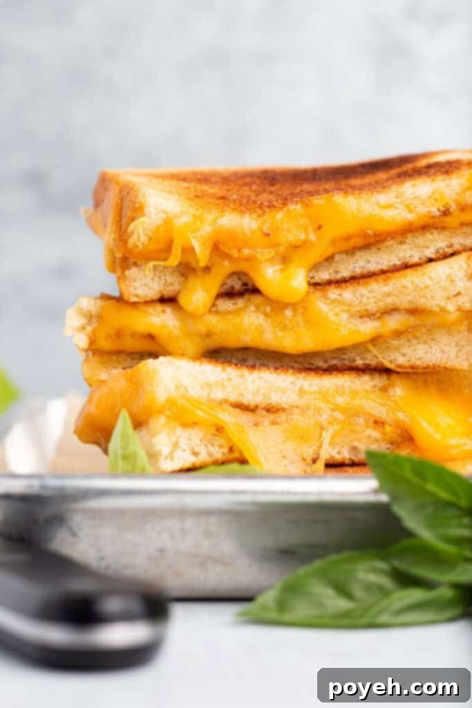 Side view of 4 toasted grilled cheese halves stacked on top of each other with cheese oozing out toward the camera.
