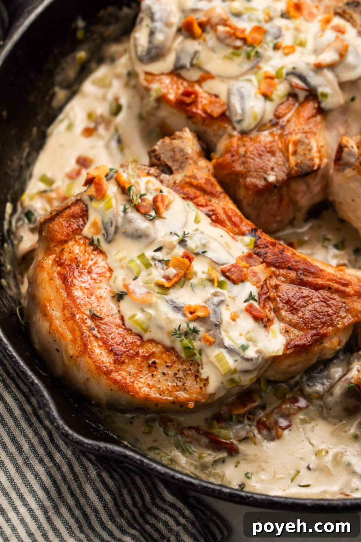 Keto smothered pork chops in a cast iron skillet with a creamy sauce.