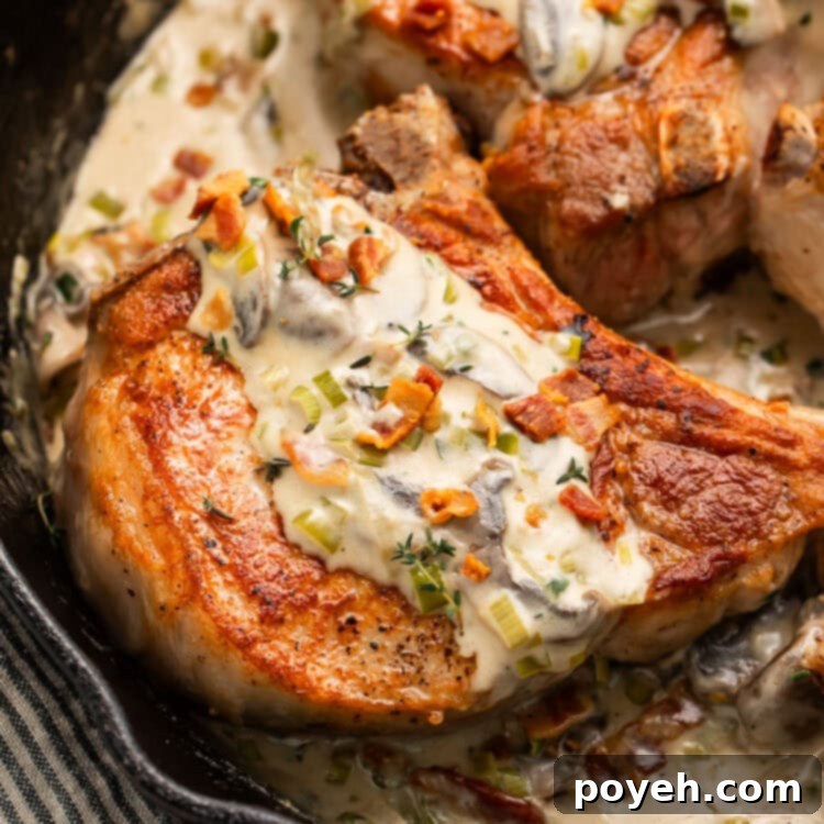 Keto smothered pork chops in a cast iron skillet with a creamy sauce.