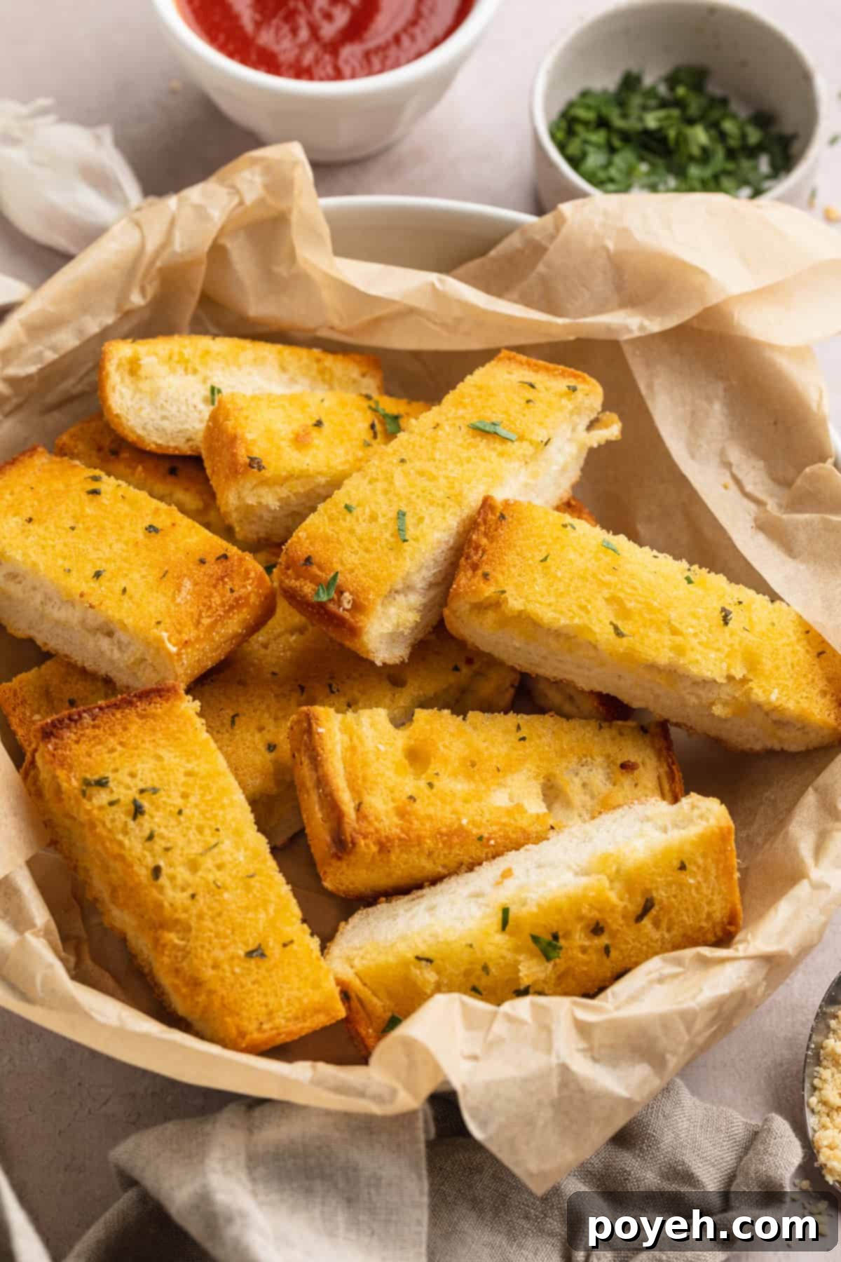Overhead angled view of frozen garlic toast cooked in the air fryer then cut into thick breadsticks and tossed in a bowl with pizza sauce.