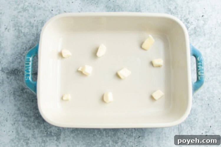 Overhead view of a 9x13 baking dish with pieces of butter distributed throughout.