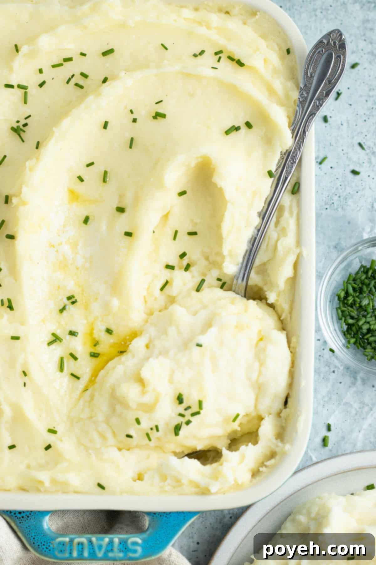 Overhead view of a casserole dish of potato mousseline with a silver spoon scooping potatoes out.