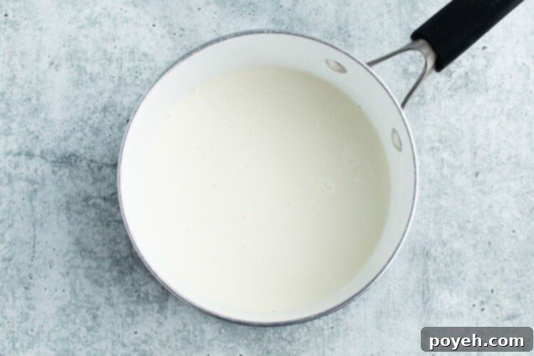Overhead view of milk and cream in a medium saucepan on a white countertop.