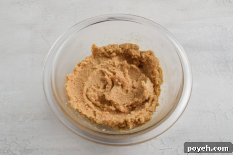 Keto cookie dough batter in a small glass mixing bowl on a white table.