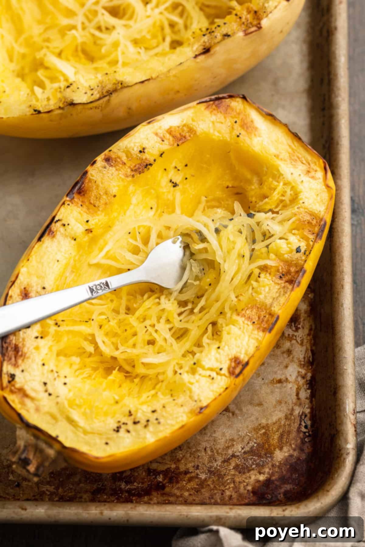 Overhead view of a grilled spaghetti squash half on a baking sheet.