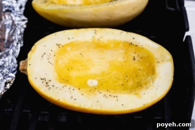 Spaghetti squash halves cut-side up on grill grates over indirect heat.