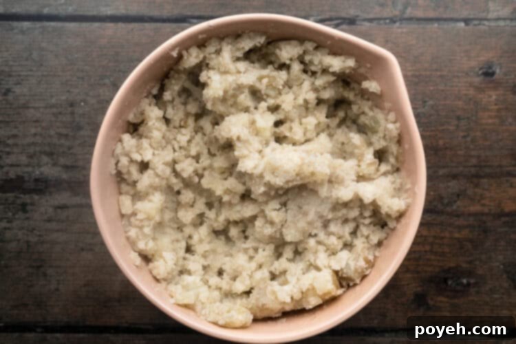 Velvety Whipped Potatoes 7 Overhead view of large beige mixing bowl holding roughly mashed potatoes after initial blending.