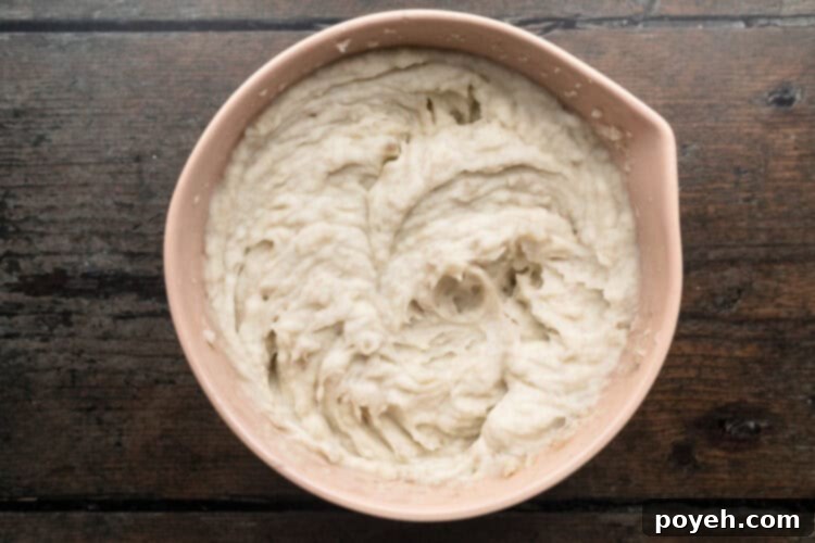 Velvety Whipped Potatoes 8 Overhead view of roughly mashed potatoes mixed with hot milk until mixture is creamy and smooth in a mixing bowl.