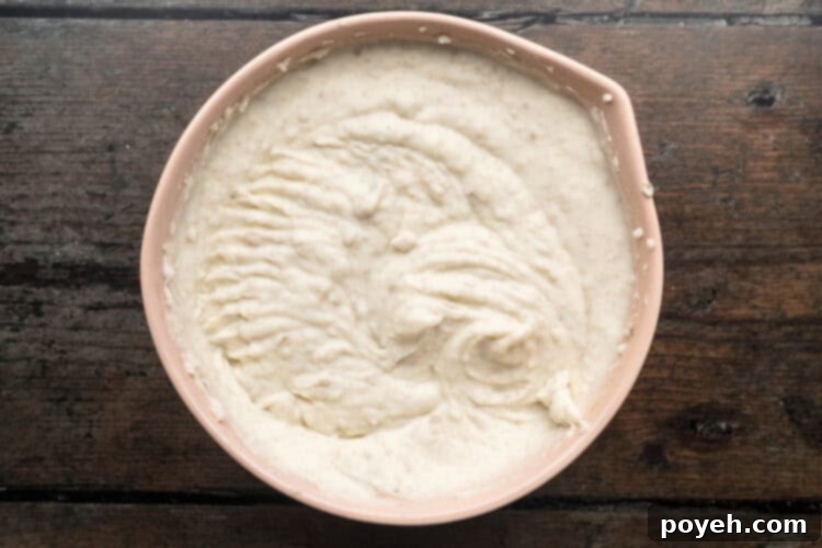 Velvety Whipped Potatoes 9 Overhead view of creamy whipped potatoes with milk, butter, and cream cheese fully incorporated in a large beige mixing bowl.