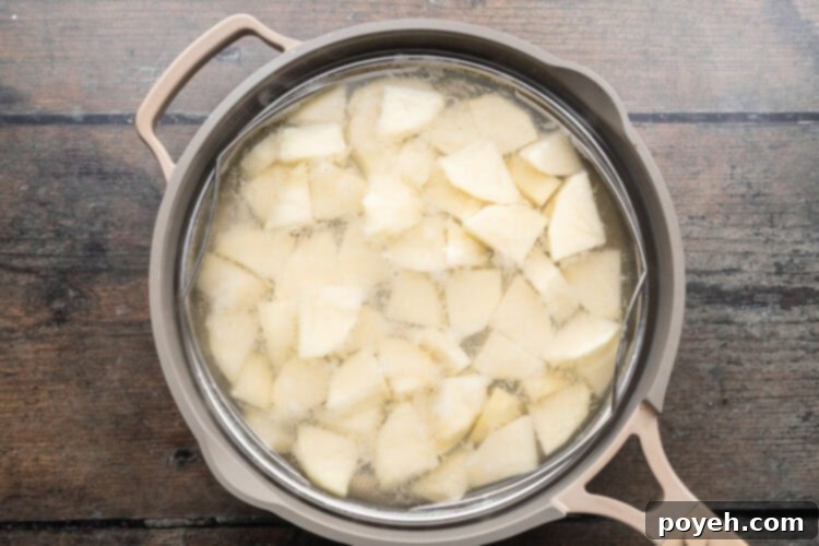 Overhead view of salted potato cubes in a large pot of water to blanch potatoes.