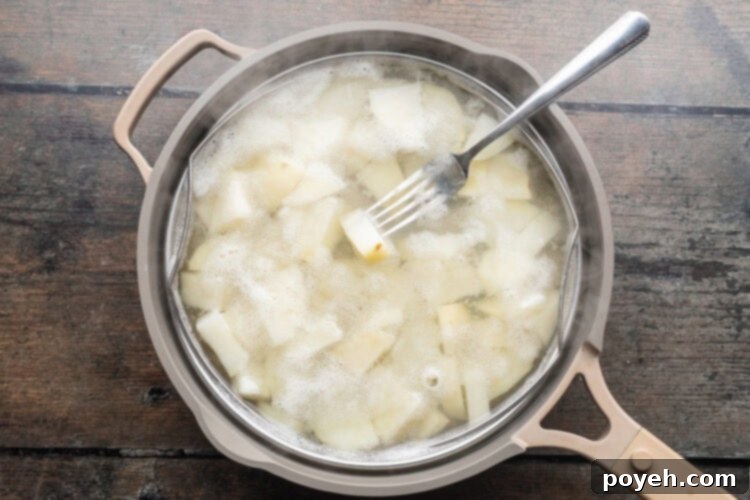 Overhead view of cubed potatoes in a large pot with simmering water.