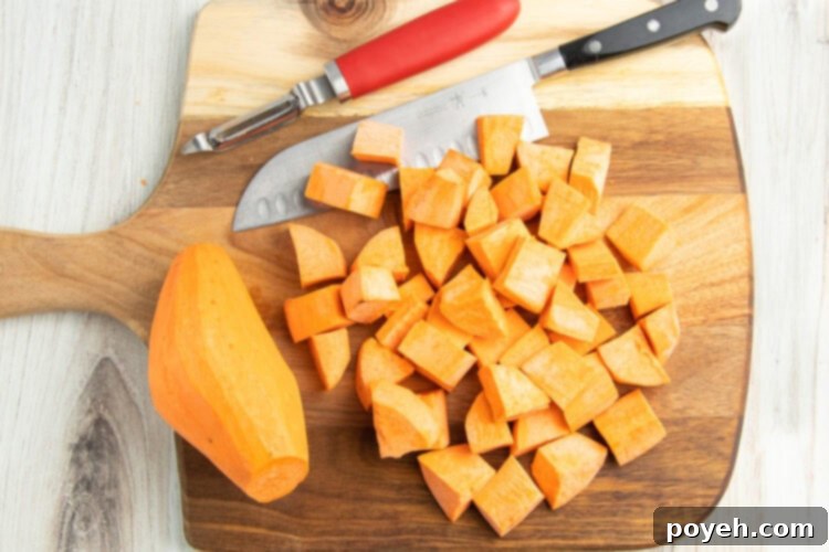 Overhead view of cubed sweet potatoes on a cutting board next to a whole sweet potato.