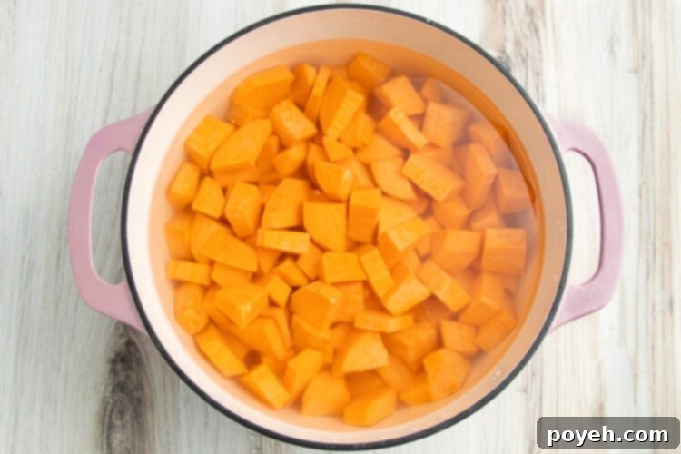 Overhead view of cubed sweet potatoes in water in a large pot.