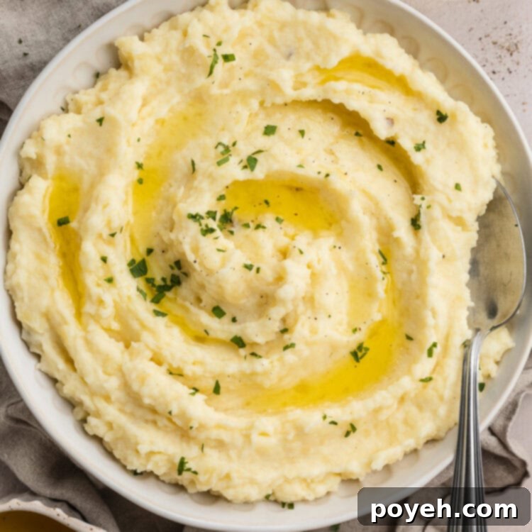 Overhead, zoomed out view of a large bowl of truffle mashed potatoes on a table set for the holidays.