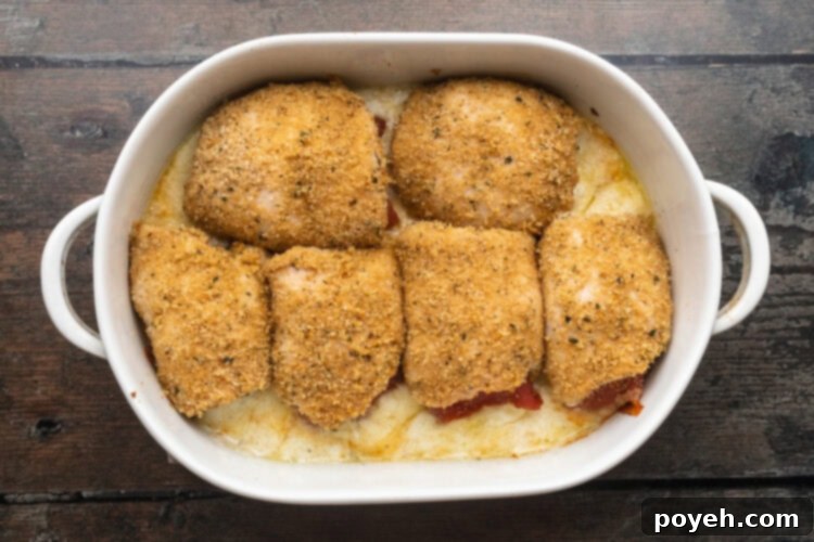 Baked chicken rollatini in a large white oval baking dish on a wooden table.