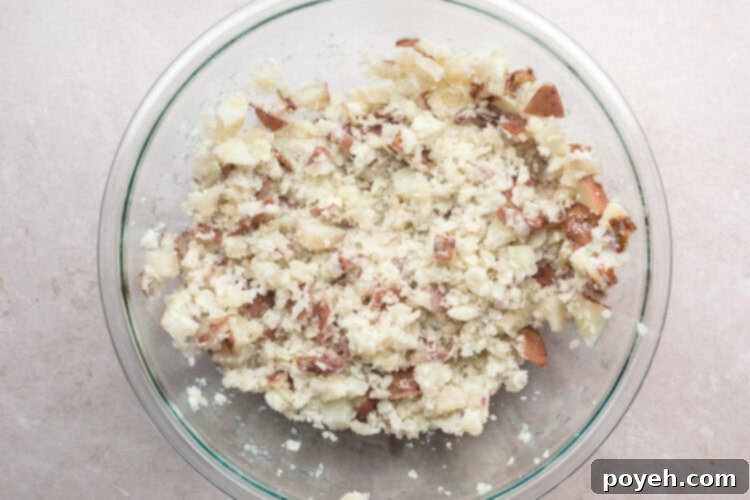 Overhead view of mashed red skin potatoes in a large glass mixing bowl.