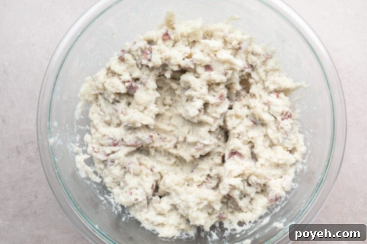 Overhead view of mashed red skin potatoes in a large glass mixing bowl.