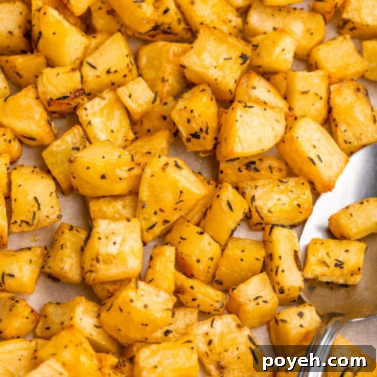 Overhead, fairly close-up view of a pile of golden-brown, crispy diced potatoes on a baking sheet, showcasing their appealing texture.
