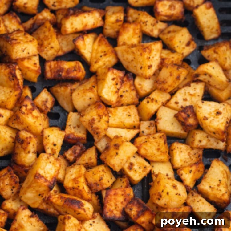 Overhead view of air fryer breakfast potatoes in an air fryer basket.