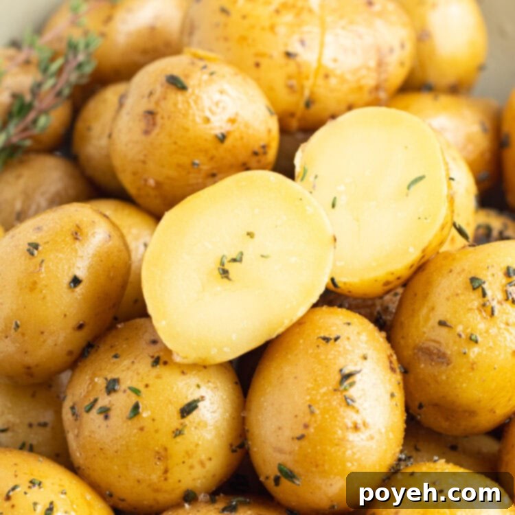Overhead, close-up view of confit potatoes in a large bowl on a white tablecloth.