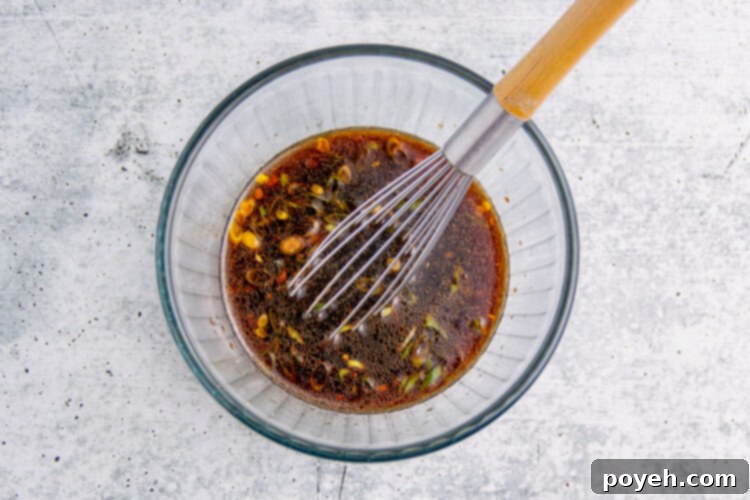 Air fryer tuna steak marinade in a glass mixing bowl with a whisk.