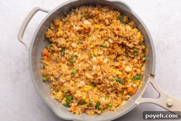 Fried rice, soy sauce, veggies, and eggs in large skillet.