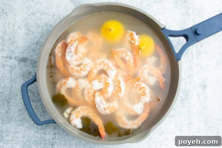 Shrimp gently poaching in the aromatic liquid within a large pot.