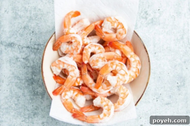 Perfectly poached and cooled shrimp neatly arranged in a bowl.