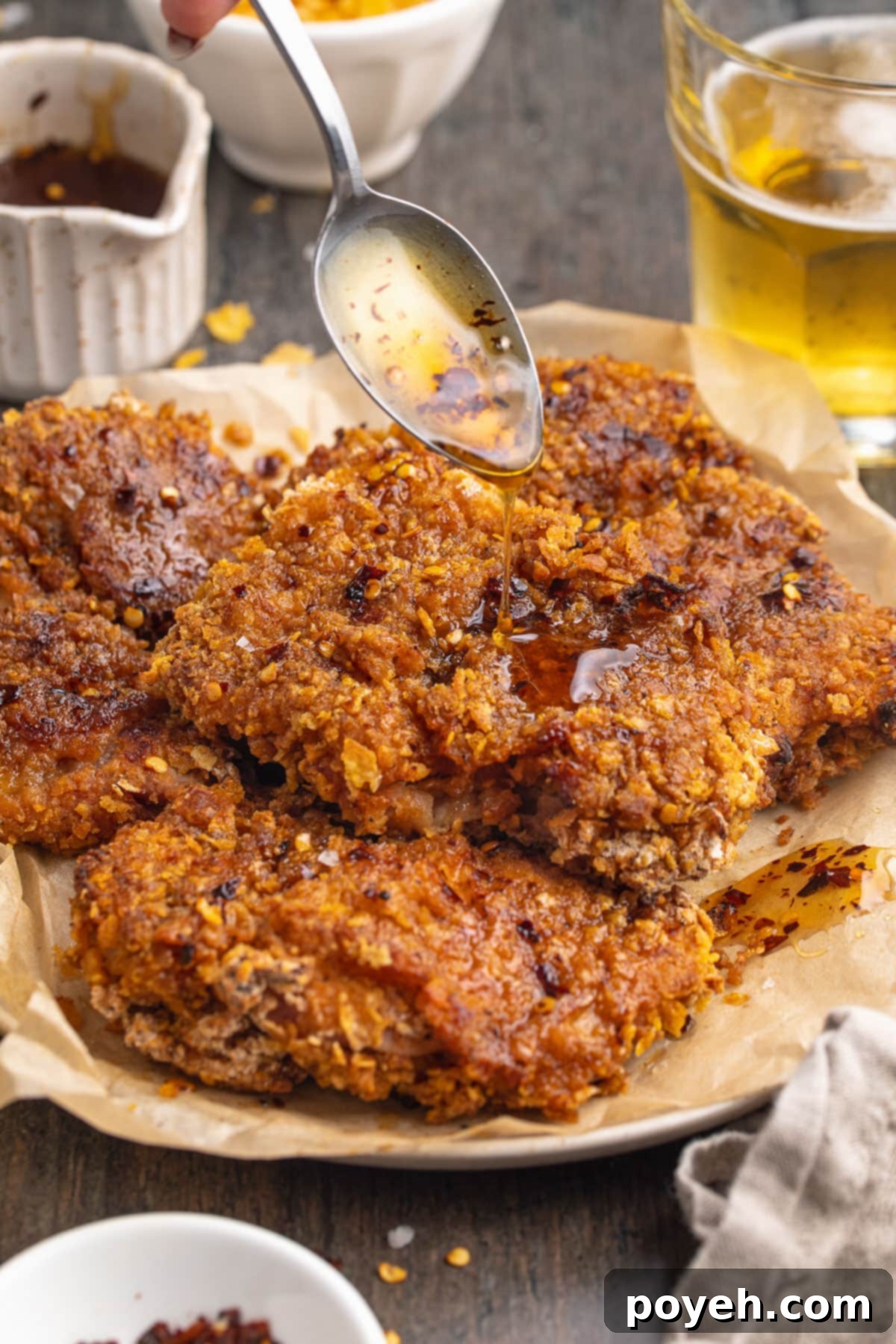 Hot honey sauce being drizzled over a crispy baked chicken breast, creating hot honey chicken.