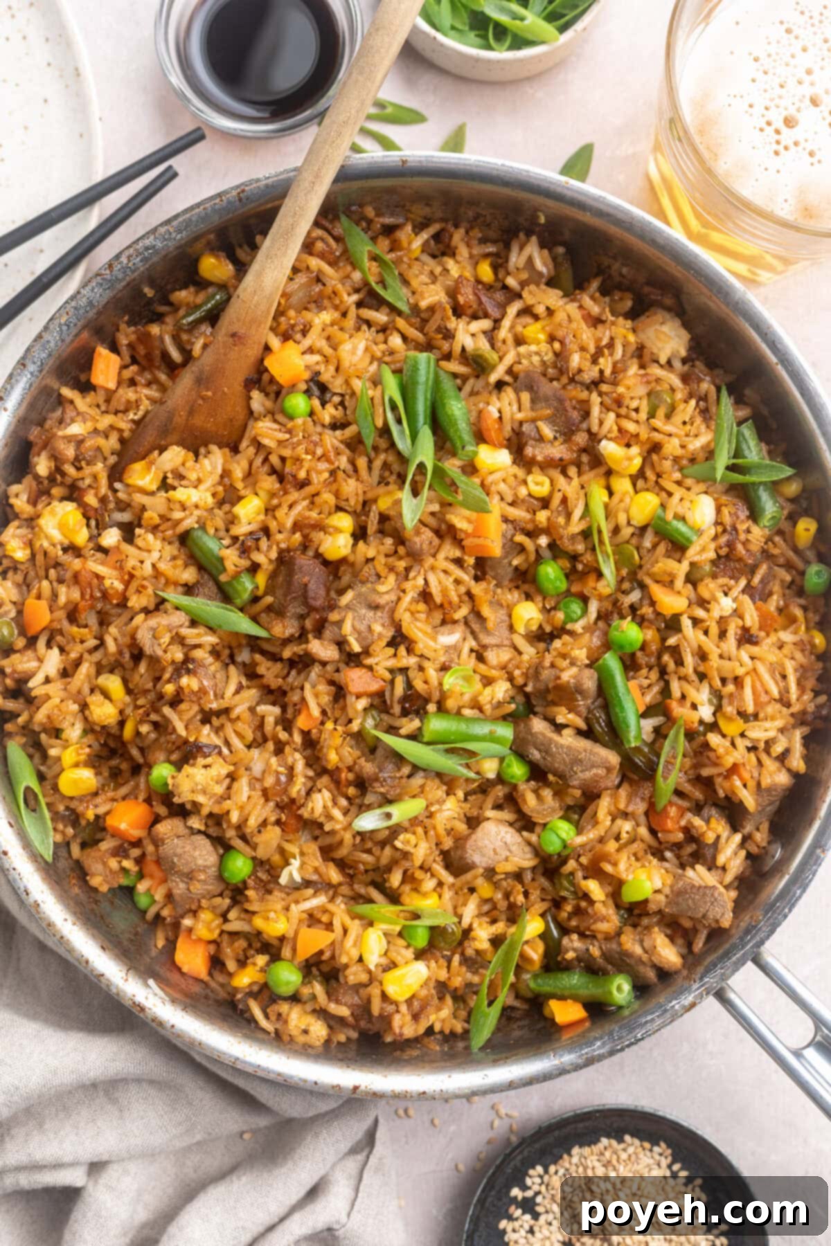 Overhead view of a large silver skillet of duck fried rice with veggies.