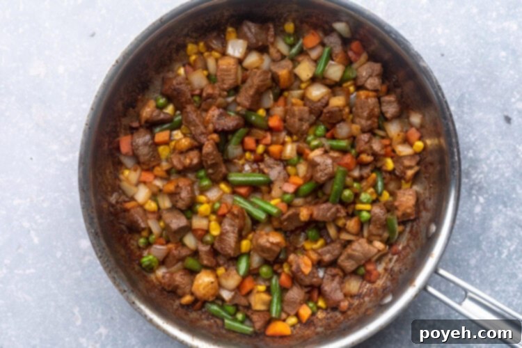 Duck breast, soy sauce, spices, and frozen mixed vegetables in a large silver skillet.