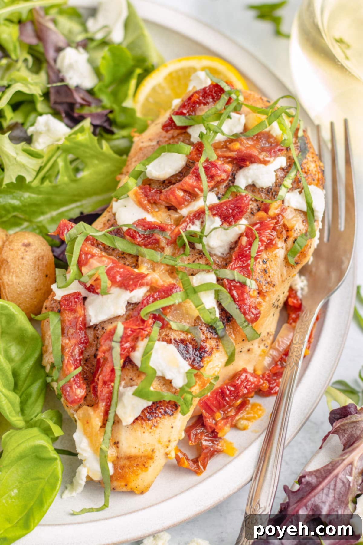 Top-down view of a chicken bryan chicken breast on a plate with baby potatoes and a small salad.