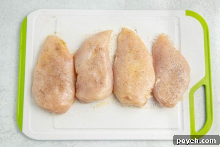 Seasoned chicken breasts on a cutting board.