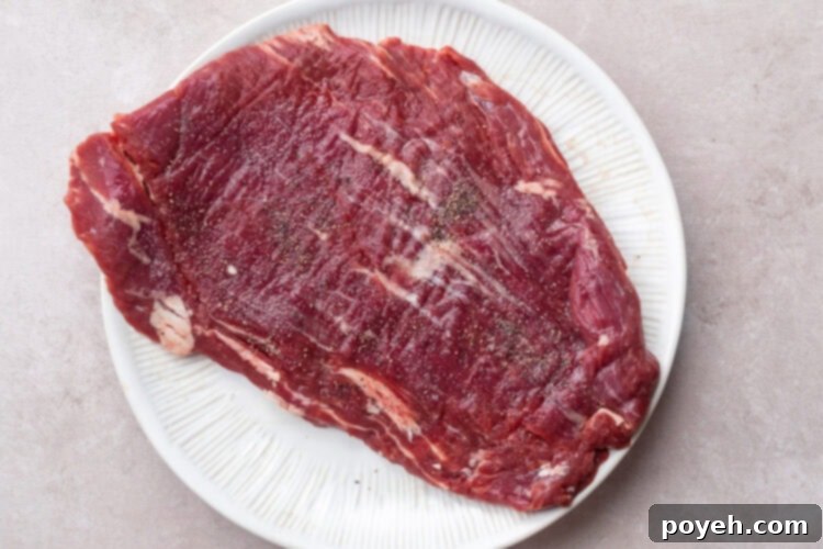 Seasoned flank steak on a round white plate.