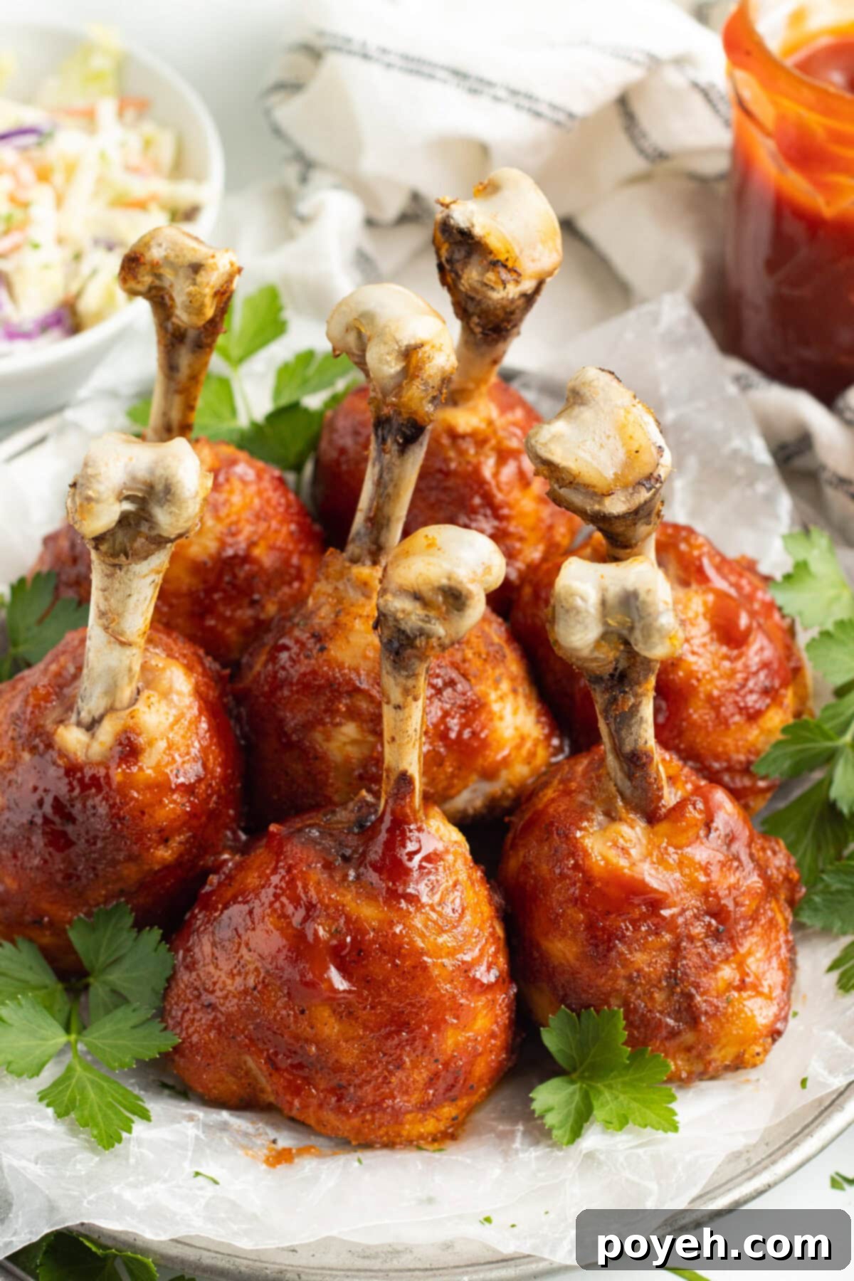 Overhead, angled view of perfectly shaped lollipop chicken legs standing upright on a white plate, ready to be served.