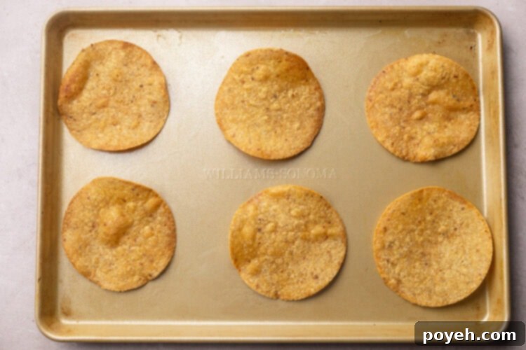 Zesty Tuna Crunch 5 6 corn tortilla tostadas on a baking sheet, crisp and lightly browned, ready for cooling.