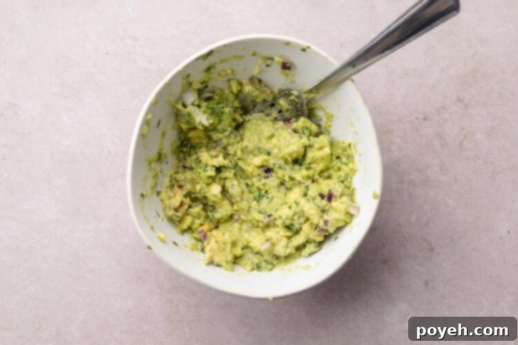 Zesty Tuna Crunch 6 Freshly made quick guacamole for tuna tostadas in a medium mixing bowl, with a fork.