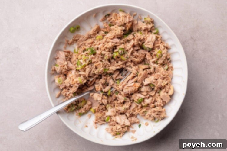 Zesty Tuna Crunch 7 Seasoned flaked tuna for tuna tostadas in a large mixing bowl, mixed with fresh herbs and spices.
