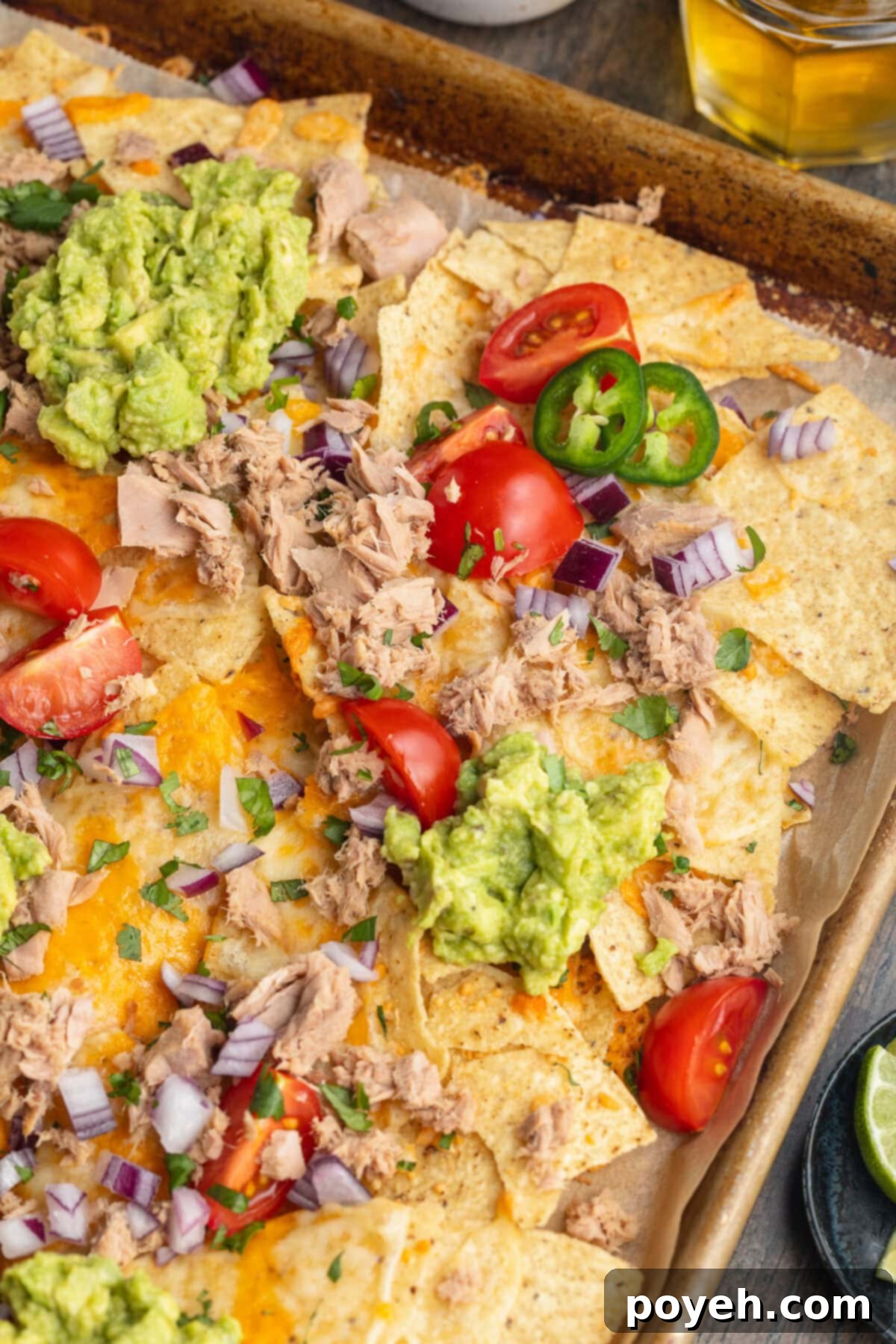 Overhead view of tuna nachos with various nacho toppings spread out across a baking sheet.