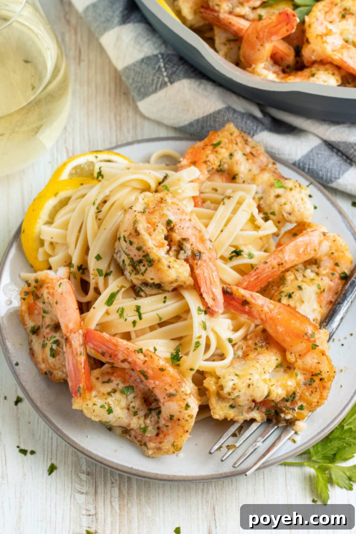 Shrimp francese on a plate, garnished with fresh parsley and lemon slices.