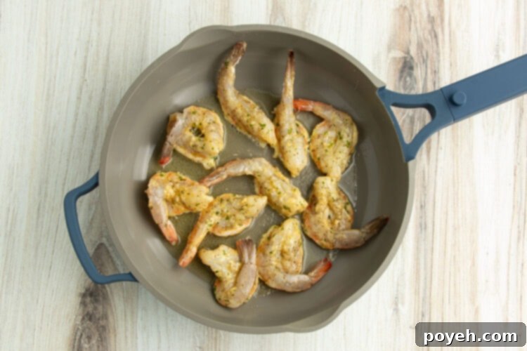 Shrimp searing to golden perfection in the hot skillet.