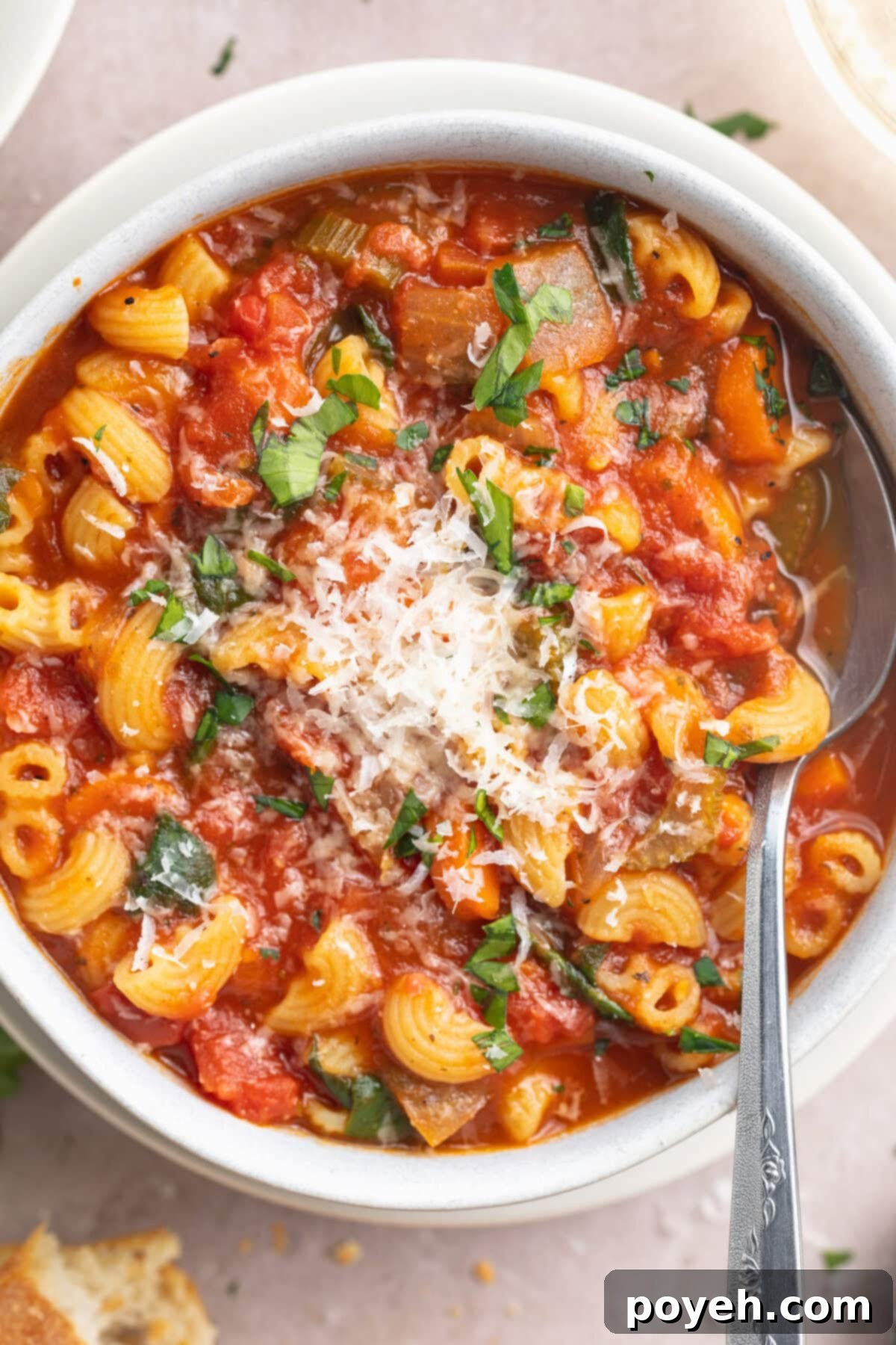 Close-up of tomato florentine soup in a large white soup bowl with a silver spoon.