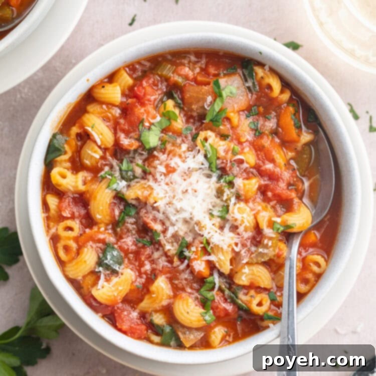 A white bowl of tomato florentine soup on a white tabletop.