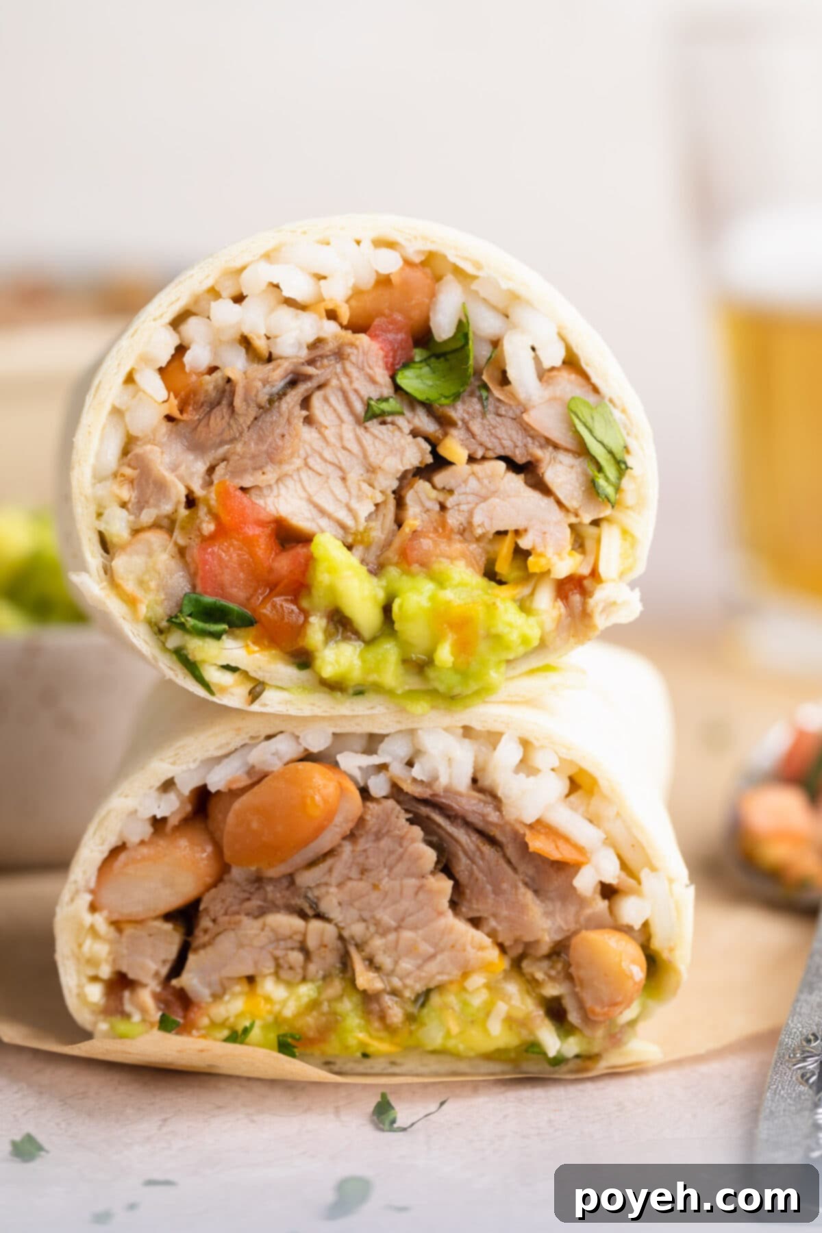 Cross section of a carnitas burrito, with the two halves stacked on top of each other to show ingredients inside.