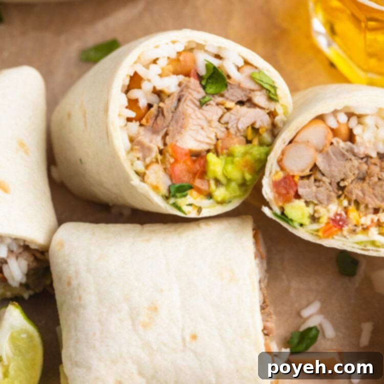 Two carnitas burritos cut in half and laying on a sheet of parchment paper.